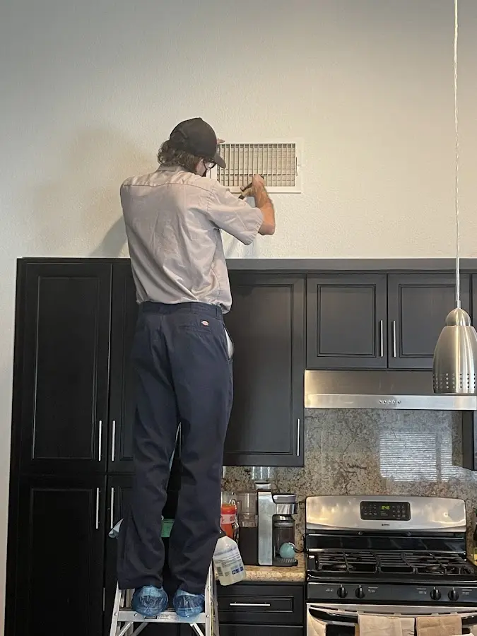 Technician inspecting an air vent during HVAC service in Vidor